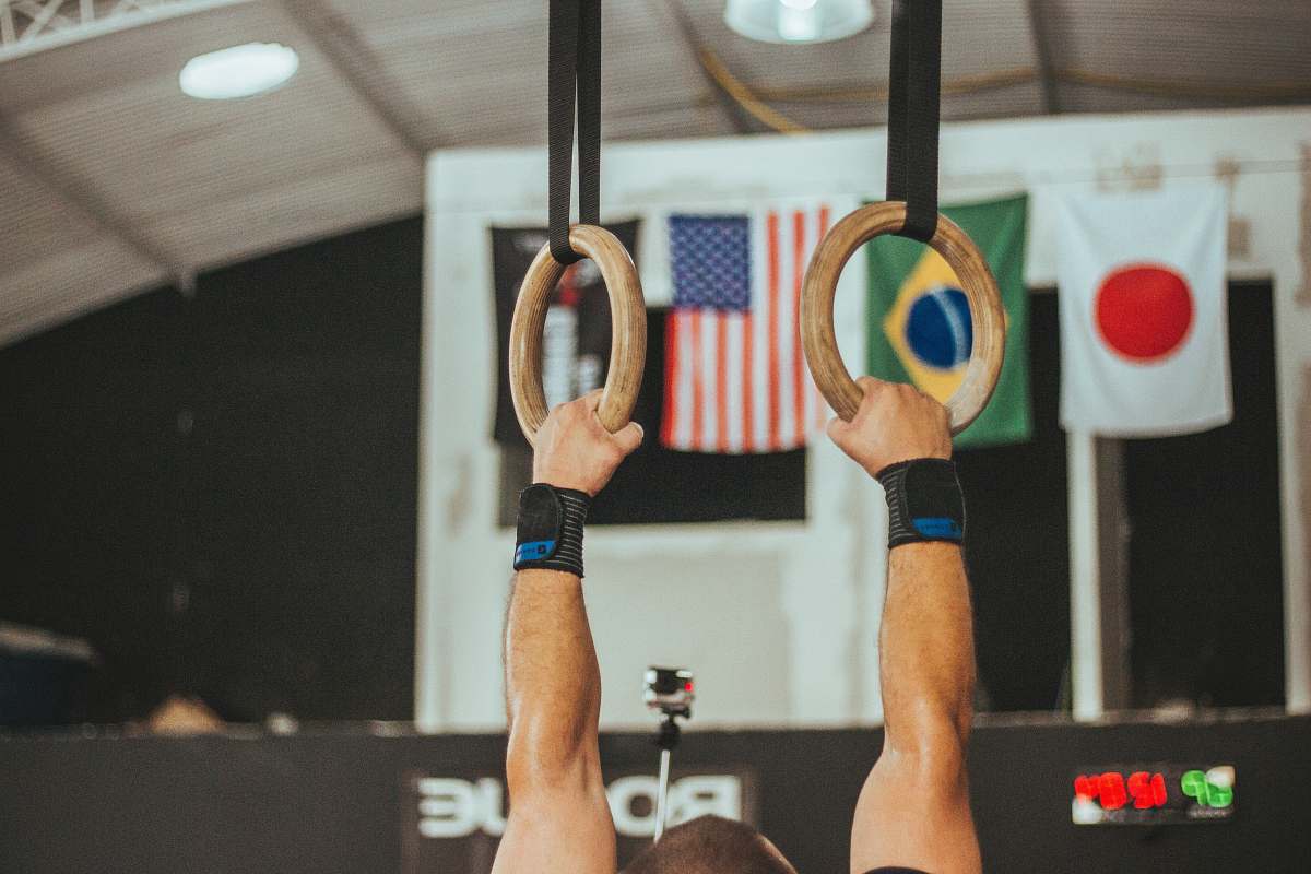 gambaru crossfit man holding two brown wooden rings working out